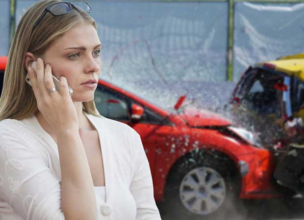 woman on the phone with a crashed red car behind her